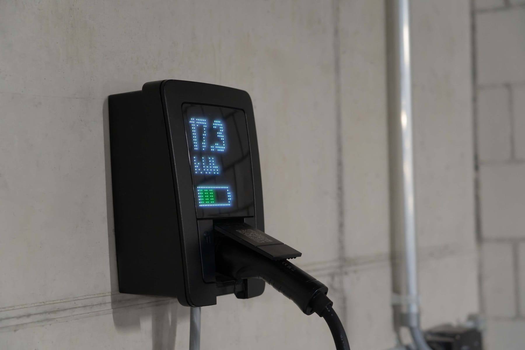 Falra szerelt elektromos autó töltő kijelzővel egy garázsban